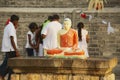Buddha statue with people praying at the background at Ruwanwelisaya stupa in Anuradhapura, Sri Lanka.