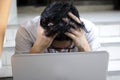 Anxiety confused young Asian business man with laptop covering face with his hands