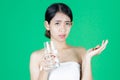 Anxiety stressed young Asian woman holding pills on hands over green isolated background. Medicine and health care concept Royalty Free Stock Photo