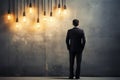 Anxious businessman, back turned, contemplates near lamp against concrete wall