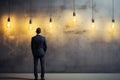 Anxious businessman, back turned, contemplates near lamp against concrete wall