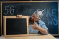 An anxious conspiracy theorist in a protective aluminum foil hat and glasses sits at a table and points his finger at a