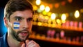 Anxious fan with argentinian flag on cheek attentively watching football match Royalty Free Stock Photo