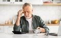 Anxious senior man managing finances, holding cash and using calculator at home Royalty Free Stock Photo