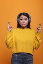Anxious stressed asian woman having crossed fingers before job interview on orange background Royalty Free Stock Photo