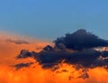 Anxious sunset. Gray and orange clouds in blue sky.