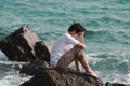 Anxious upset young Asian man covering face with hands at sea coast