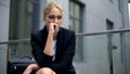 Anxious woman sitting on bench, worried about dismissal from work, depression