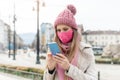 Anxious woman wearing corona mask checking news on her phone