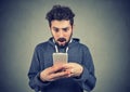 Anxious young man looking at mobile phone seeing bad news Royalty Free Stock Photo