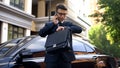 Anxious young man talking on phone, looking at watch, late for meeting