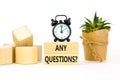 Any questions symbol. Concept words Any questions on wooden blocks on a beautiful white table white background. Black alarm clock Royalty Free Stock Photo