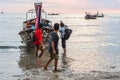 People tourists disembark from Thai long-tail boat on coast in the evening