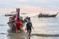 People tourists disembark from Thai long-tail boat on coast in the evening