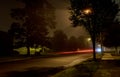 Apartment block on empty night city street covered with fog, blurred city lights glow through misty haze Royalty Free Stock Photo