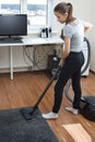 Apartment cleaning.A young European girl with long hair vacuuming a room