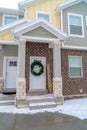 Apartment entrance with snowy steps leading to front door with holiday wreath