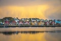 Apartment houses at the waterfront in Ballstad in front of yellow clouds at dawn