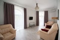 Apartment interior with large windows with curtains, beige armchairs and sofa Royalty Free Stock Photo