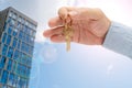 Apartment key in a man`s hand. Brass house door lock key. High-rise buildings of modern city. Royalty Free Stock Photo