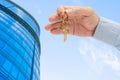 Apartment key in a man`s hand. Brass house door lock key. Modern building, view from below. Architecture in modern city. Royalty Free Stock Photo