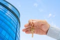 Apartment key in a man`s hand. Brass house door lock key. Modern building, view from below. Architecture in modern city. Royalty Free Stock Photo