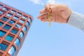 Apartment key in a man`s hand. Brass house door lock key. Modern building, view from below. Architecture in modern city. Royalty Free Stock Photo