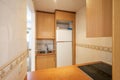 apartment kitchen with wood-colored cabinets, pass-thru window above