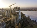 Apartment or office tall building under construction, top view. Tower crane and city landscape stretching to horizon. Drone aerial Royalty Free Stock Photo