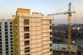 Apartment or office tall unfinished building under construction. Brick wall in scaffolding, shiny windows and tower crane on urban Royalty Free Stock Photo