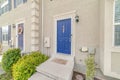 Apartment unit with vibrant blue front door and concrete steps at the entrance