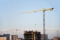 Tower crane constructing a new residential building at a construction site against blue sky Royalty Free Stock Photo