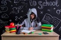 Apathetic and uninterested youngster sitting at the desk with a straight view to the camera with the view under the