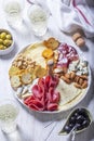 Aperitif, champagne and snack of sausage, cheese, nuts, olives and crackers on a light background.