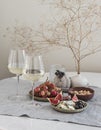 Aperitif table - two glasses of white wine, fruit, cheese, nuts on the table Royalty Free Stock Photo