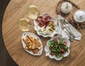 Aperitif, tapas, appetizer arugula table, cherry salad, plate with prosciutto, olives, cheese and breadsticks, cracker on a wooden