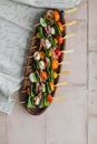 Apetizers on wooden skewers. Snacks from mozzarella, cherry tomatoes, salmon, spinach and olives.