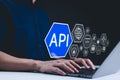 API - Application Programming Interface Concept. A programmer types on a laptop, with digital icons representing technology and Royalty Free Stock Photo