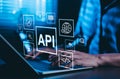 API Application Programming Interface Concept. A programmer types on a laptop, interacting with digital icons representing API Royalty Free Stock Photo