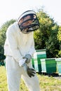 apiarist in beekeeping suit putting on