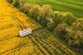 Apiary trailer with beehive crates in canola field, aerial shot from drone pov