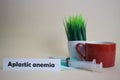 Aplastic anemia text, grass pot, coffee cup, syringe, and face green mask Royalty Free Stock Photo