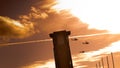 Three apache helicopters flying past a tower with clouds