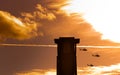 Three apache helicopters flying past a tower with clouds