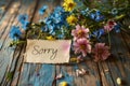 Apology note with Sorry handwritten amidst fresh wildflowers