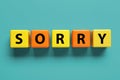 Apology. Word Sorry made of colorful cubes on turquoise background, top view
