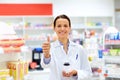 Apothecary with drug showing thumbs up at pharmacy Royalty Free Stock Photo