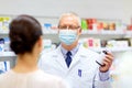Apothecary in mask with drug and woman at pharmacy Royalty Free Stock Photo