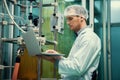 Apothecary scientist working with laptop near CBD oil extractor in laboratory.