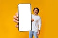 App ad. Excited man holding smartphone with white blank screen in hand close up to camera, mockup Royalty Free Stock Photo